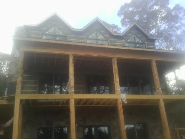 Dormers and porch framing on a large log home under construction — Roof Coating work by our crew in Coal City