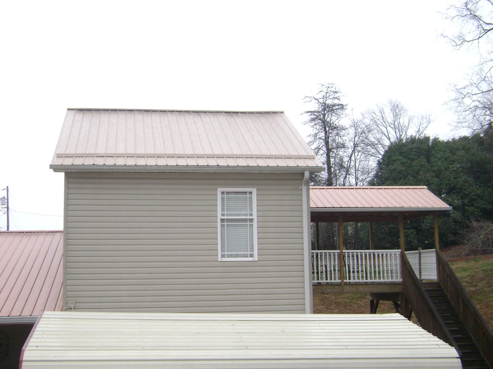 Tan metal roofs on a two story addition and attached porch, from a Roof Replacement job in Coal City